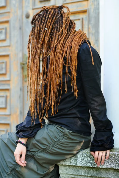 Dreadlocks fashionable girl posing at old wooden door background. side view with no face visible — Stock Photo, Image