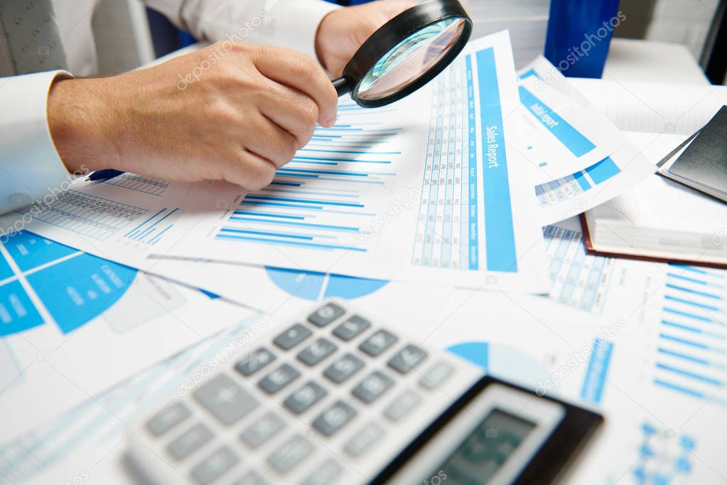 Businessman working and calculating, reads and writes reports. Office employee, table closeup. Business financial accounting concept.