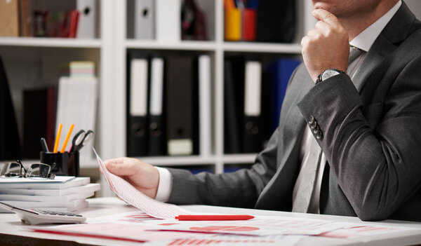 Businessman working and calculating, reads and writes reports. Office employee, table closeup. Business financial accounting concept.