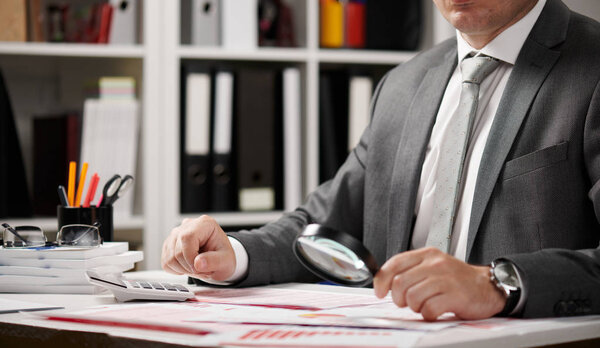 Businessman working and calculating, reads and writes reports. Office employee, table closeup. Business financial accounting concept.