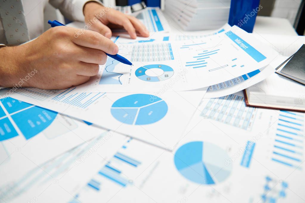 Businessman working and calculating, reads and writes reports. Office employee, table closeup. Business financial accounting concept.