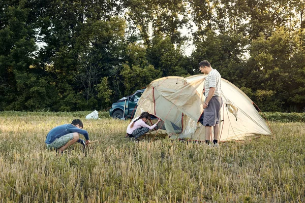 Familia estableció campamento de carpa al atardecer, hermoso paisaje de verano. Turismo, senderismo y viajes en la naturaleza . — Foto de Stock