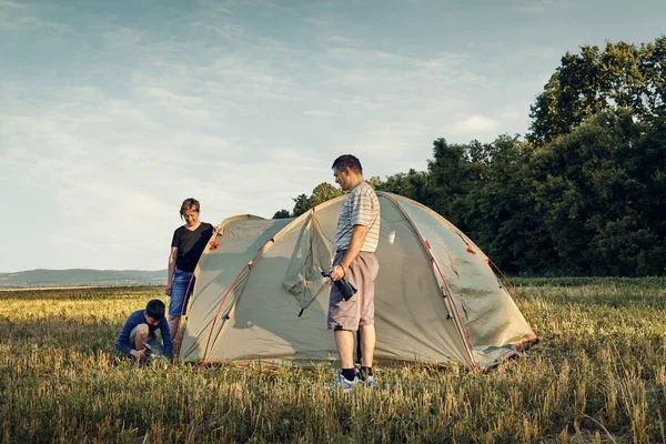 Familj inrätta tältläger vid solnedgången, vackra sommar landskap. Turism, vandring och resor i naturen. — Stockfoto