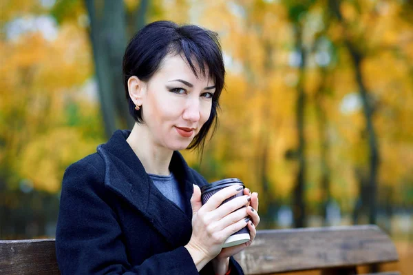 Mulher bonita posando e sonhando com xícara de café no outono parque da cidade, temporada de outono, folhas amarelas — Fotografia de Stock