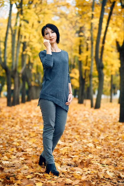 Красивая женщина позирует в осеннем городском парке, осенний сезон, желтые листья — стоковое фото