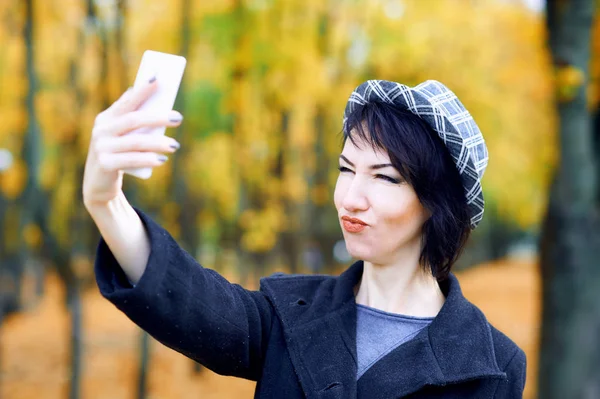 Mulher bonita tirando selfie por smartphone e se divertindo no parque da cidade de outono, temporada de outono, folhas amarelas — Fotografia de Stock