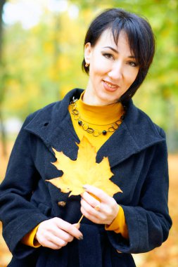 Sonbahar şehir parkında sarı yapraklarla poz veren güzel kadın, sonbahar mevsimi