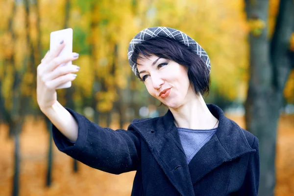 Vacker kvinna tar Selfie med smartphone och ha kul i höst stadsparken, höstsäsongen, gula löv — Stockfoto