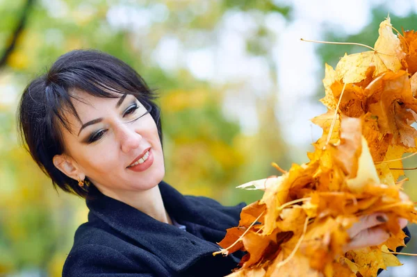 Beautiful woman posing with yellow leaves in autumn city park, fall season — Stock Photo, Image