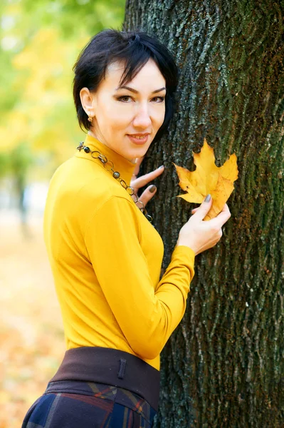 Hermosa mujer posando con hojas amarillas en el parque de otoño de la ciudad, temporada de otoño — Foto de Stock