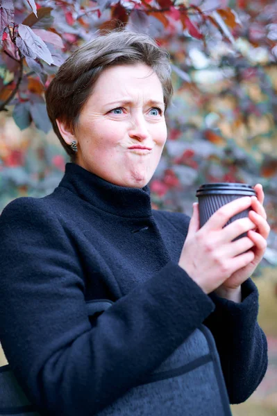 Mulher bonita posando com xícara de papel de chá ou café no parque da cidade de outono, temporada de outono — Fotografia de Stock