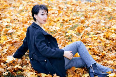 Sonbahar şehir parkında sarı yapraklarla poz veren güzel kadın, sonbahar mevsimi
