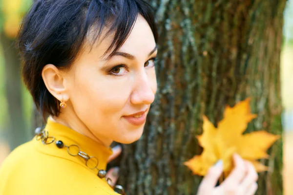 Hermosa mujer posando con hojas amarillas en el parque de otoño de la ciudad, temporada de otoño — Foto de Stock