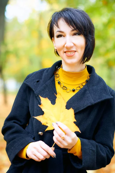 Bella donna in posa con foglie gialle nel parco della città di autunno, stagione autunnale — Foto Stock