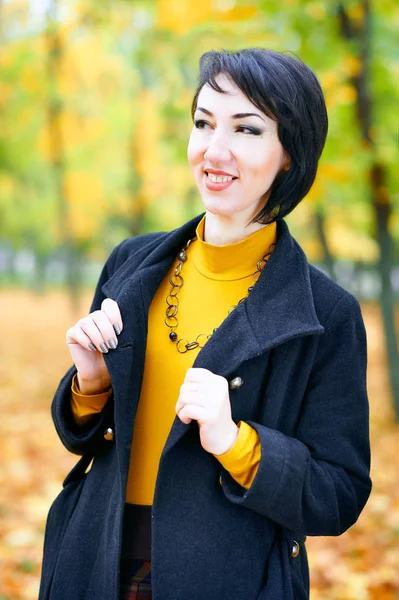 Piękna kobieta pozuje z żółtymi listwami w jesiennym parku miejskim, jesienią sezonu — Zdjęcie stockowe