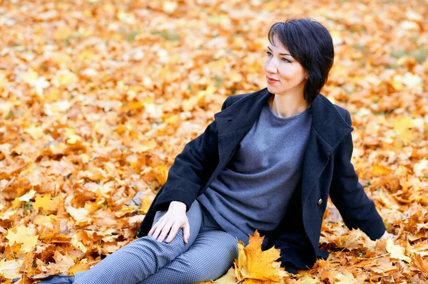 Krásná žena s žlutými listy v podzimním městském parku, podzimní sezóna — Stock fotografie