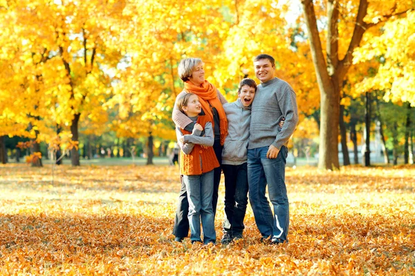 Lycklig familj poserar, leker och har roligt i höst stadsparken. Barn och föräldrar tillsammans med en trevlig dag. Starkt solljus och gula löv på träd, höstsäsongen. — Stockfoto