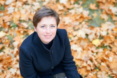 Sonbahar şehir parkında sarı yapraklarla poz veren güzel kadın, sonbahar mevsimi