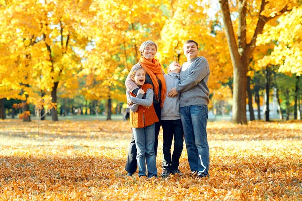 Lycklig familj poserar, leker och har roligt i höst stadsparken. Barn och föräldrar tillsammans med en trevlig dag. Starkt solljus och gula löv på träd, höstsäsongen. — Stockfoto