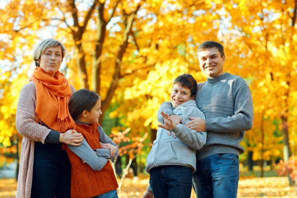 Gelukkige familie poseren, spelen en plezier hebben in het herfst stadspark. Kinderen en ouders samen met een mooie dag. Fel zonlicht en gele bladeren op bomen, herfst seizoen. — Stockfoto