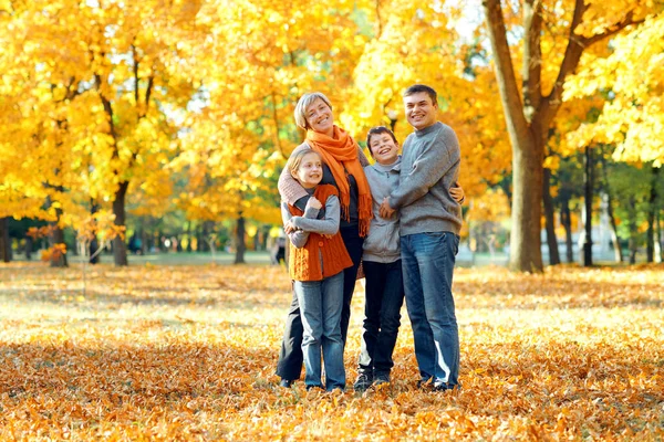Szczęśliwa rodzina pozowanie, gry i zabawy w jesiennym parku miejskim. Dzieci i rodzice razem o miłym dniu. Jasne światło słoneczne i żółte liście na drzewach, jesień sezonu. — Zdjęcie stockowe