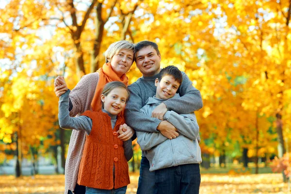 Família feliz posando, jogando e se divertindo no parque da cidade de outono. Crianças e pais juntos tendo um bom dia. Luz solar brilhante e folhas amarelas em árvores, estação de outono . — Fotografia de Stock