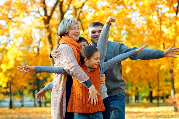 Gelukkige familie poseren, spelen en plezier hebben in het herfst stadspark. Kinderen en ouders samen met een mooie dag. Fel zonlicht en gele bladeren op bomen, herfst seizoen. — Stockfoto