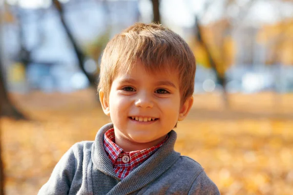 Happy child playing, posing, smiling and having fun in autumn city park. Bright yellow trees and leaves — Stock Photo, Image