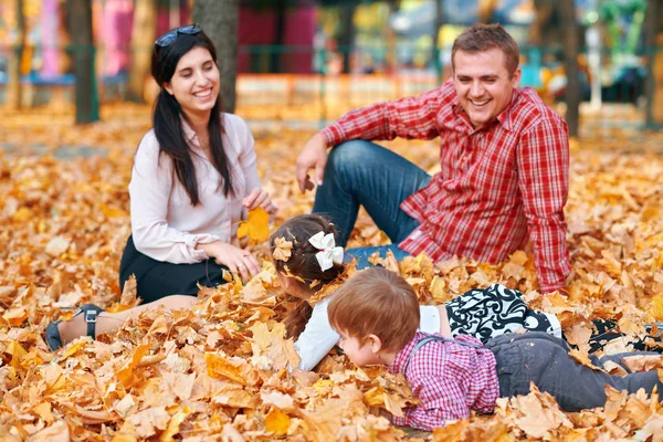 Bonne famille ayant des vacances dans le parc de la ville d'automne. Enfants et parents posant, souriant, jouant et s'amusant. Feuilles et arbres jaune vif — Photo