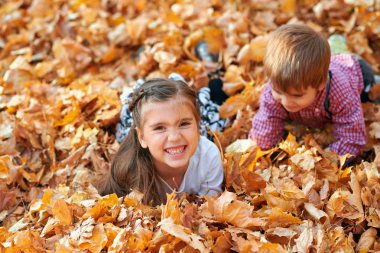Mutlu çocuklar oynarken, poz, gülümsüyor ve sonbahar şehir parkında eğleniyor. Parlak sarı ağaçlar ve yapraklar