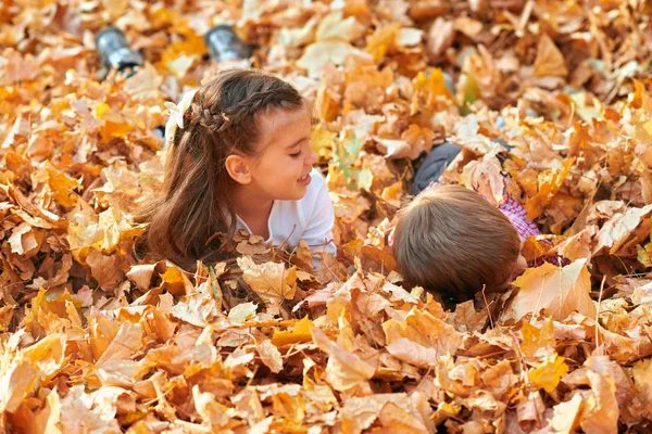 Enfants heureux jouant, posant, souriant et s'amusant dans le parc de la ville d'automne. Feuilles et arbres jaune vif — Photo