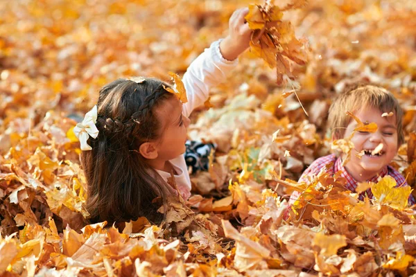 Enfants heureux jouant, posant, souriant et s'amusant dans le parc de la ville d'automne. Feuilles et arbres jaune vif — Photo