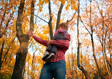 Çocuklar ve baba oynarken ve sonbahar şehir parkında tatil. Poz vermek, gülümsemek, oynamak ve eğlenmek. Parlak sarı ağaçlar ve yapraklar