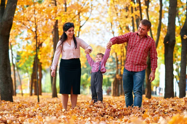 Mutlu aile sonbahar şehir parkında tatil yapıyor. Çocuklar ve ebeveynler poz veriyor, gülümsüyor, oynuyor ve eğleniyorlar. Parlak sarı ağaçlar ve yapraklar — Stok fotoğraf
