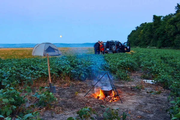 Famiglia in viaggio e in campeggio, crepuscolo, cucina sul fuoco. Bella natura - campo, foresta e luna . — Foto Stock