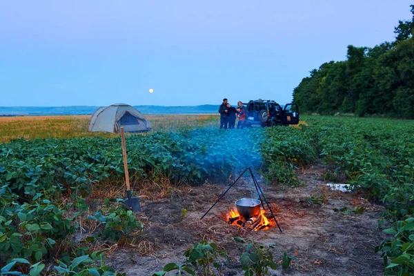 Famiglia in viaggio e in campeggio, crepuscolo, cucina sul fuoco. Bella natura - campo, foresta e luna . — Foto Stock