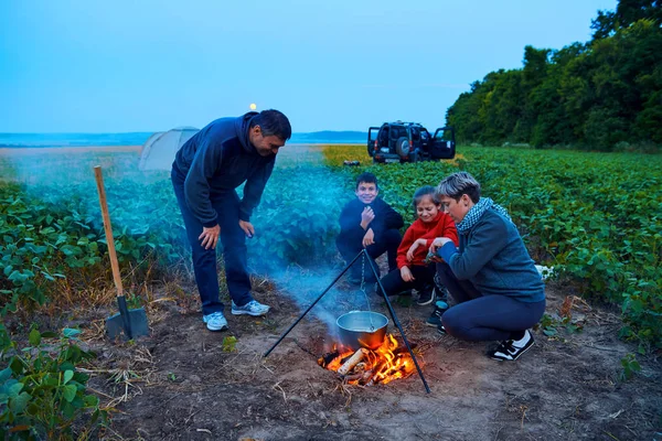 Famiglia in viaggio e in campeggio, crepuscolo, cucina sul fuoco. Bella natura - campo, foresta e luna . — Foto Stock