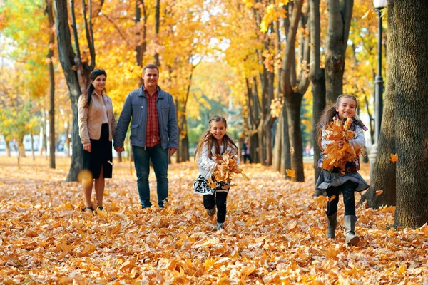 Famiglia felice avendo vacanza nel parco della città di autunno. Bambini e genitori in posa, sorridendo, giocando e divertendosi. Luminosi alberi e foglie gialle — Foto Stock