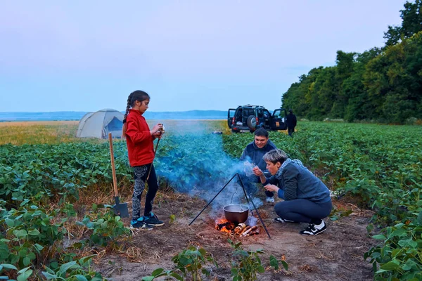 Famiglia in viaggio e in campeggio, crepuscolo, cucina sul fuoco. Bella natura - campo, foresta e luna . — Foto Stock