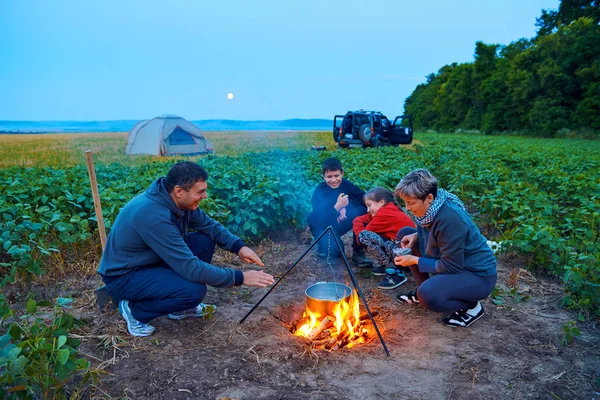 Famiglia in viaggio e in campeggio, crepuscolo, cucina sul fuoco. Bella natura - campo, foresta e luna . — Foto Stock