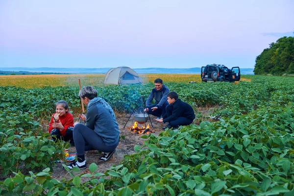 Famiglia in viaggio e in campeggio, crepuscolo, cucina sul fuoco. Bella natura - campo, foresta e luna . — Foto Stock