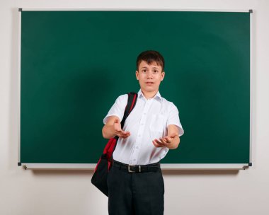 Bir okul çocuğunun kara tahta arka plan üzerinde sırt çantası ile poz portresi - geri okul ve eğitim kavramı