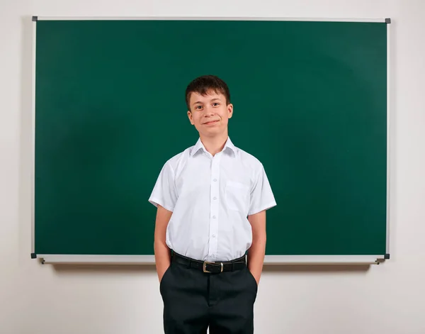 Portrait of a school boy posing on blackboard background - back to school and education concept — Stock Photo, Image