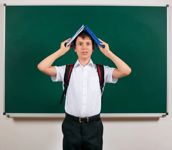 Retrato de um menino da escola posando com mochila e material escolar, fundo de quadro-negro - de volta ao conceito de escola e educação — Fotografia de Stock