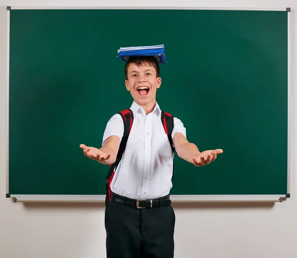 Ritratto di uno scolaro in posa con zaino e materiale scolastico, sfondo lavagna - ritorno a scuola e concetto di istruzione — Foto Stock