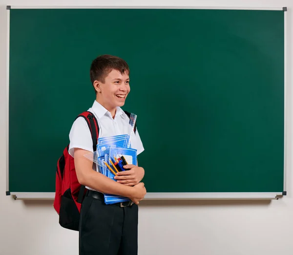 Πορτρέτο ενός σχολείου αγόρι που ποζάρει με σακίδια και σχολικές προμήθειες, πίνακα φόντο-πίσω στο σχολείο και την εκπαίδευση έννοια — Φωτογραφία Αρχείου