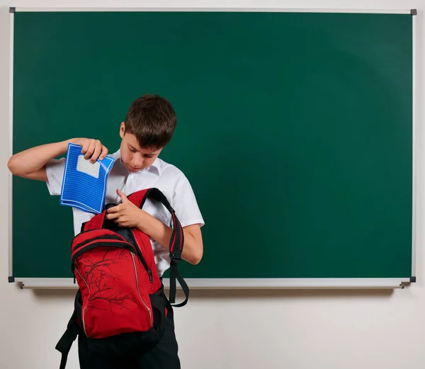 Πορτραίτο ενός αγοριού που έψαχνε για σχολικές προμήθειες στο σακίδιο του, το φόντο του μαυροπίνακα-πίσω στο σχολείο και την εκπαίδευση — Φωτογραφία Αρχείου