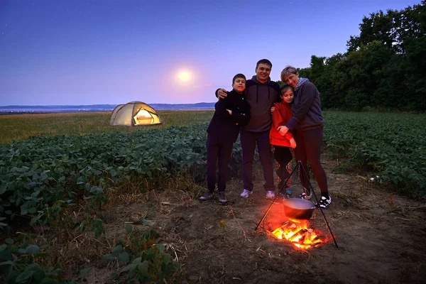 Famiglia in viaggio e in campeggio, crepuscolo, cucina sul fuoco. Bella natura - campo, foresta, stelle e luna . — Foto Stock