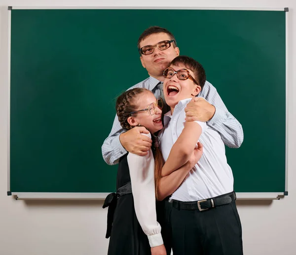 一个老师，小学生和女学生的肖像，用老式眼镜在黑板背景上摆姿势 - 回到学校和教育概念 — 图库照片
