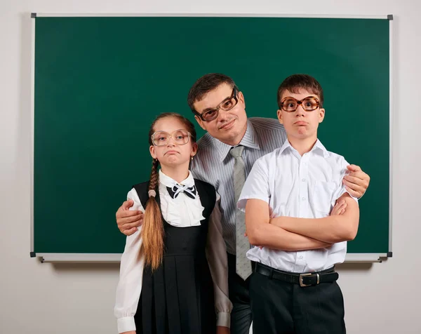 黒板の背景にポーズをとる昔ながらの眼鏡をかけた教師、男子生徒、女子高生の肖像画 - 学校や教育の概念に戻る ロイヤリティフリーのストック写真